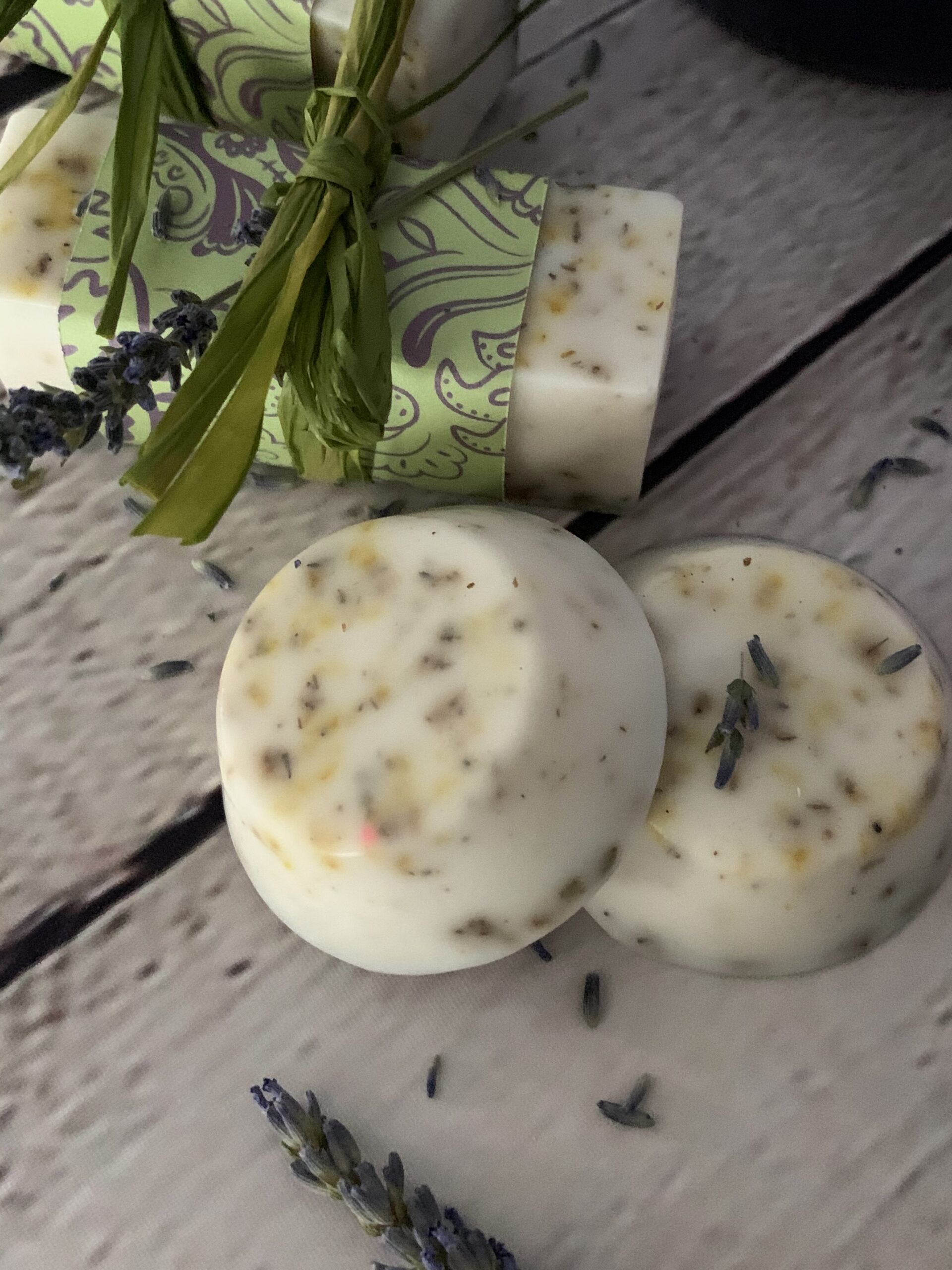 lemon and lavender soap sitting on the table with lavender petals sprinkled all around