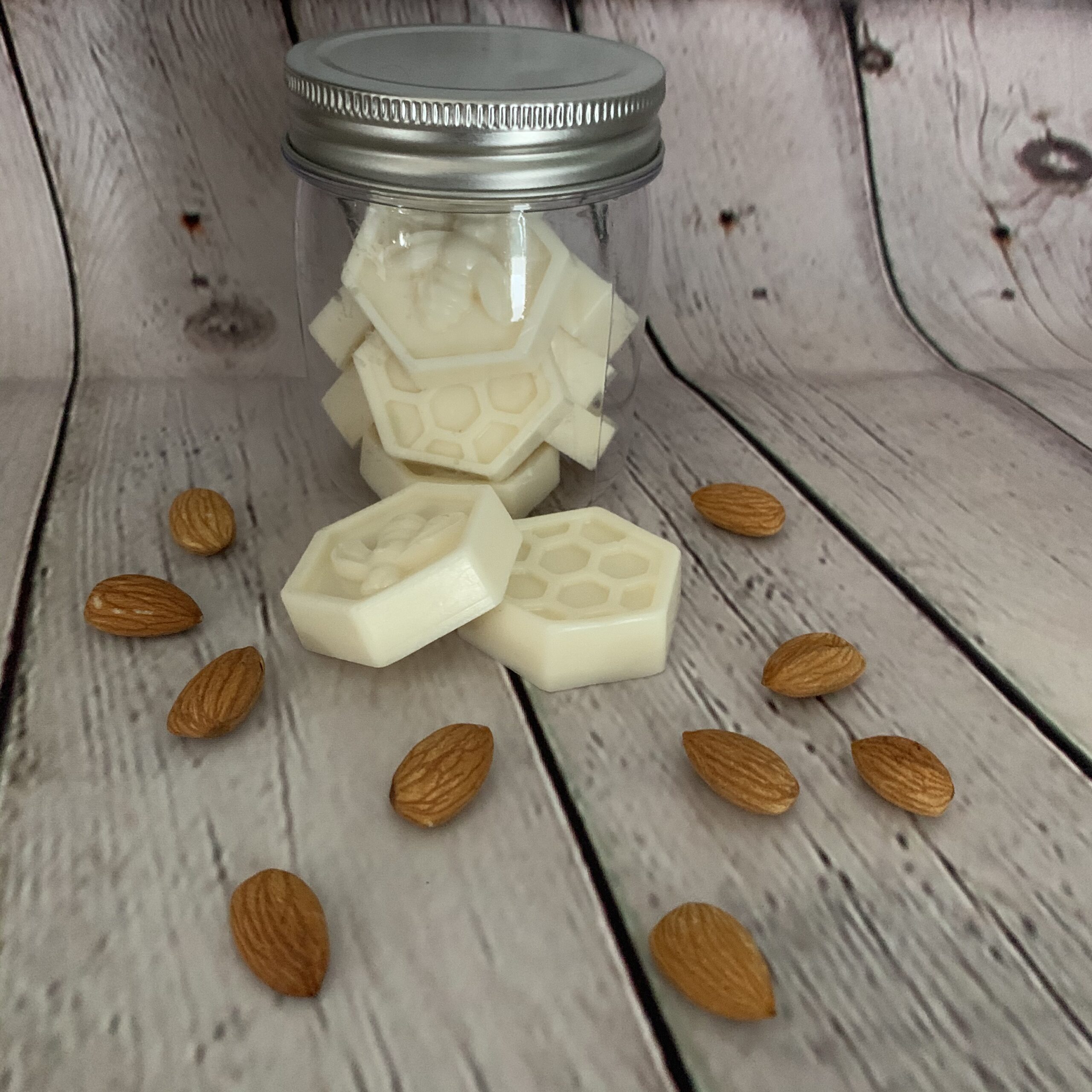 milk and honey soaps loose and in a container and almonds scattered all around